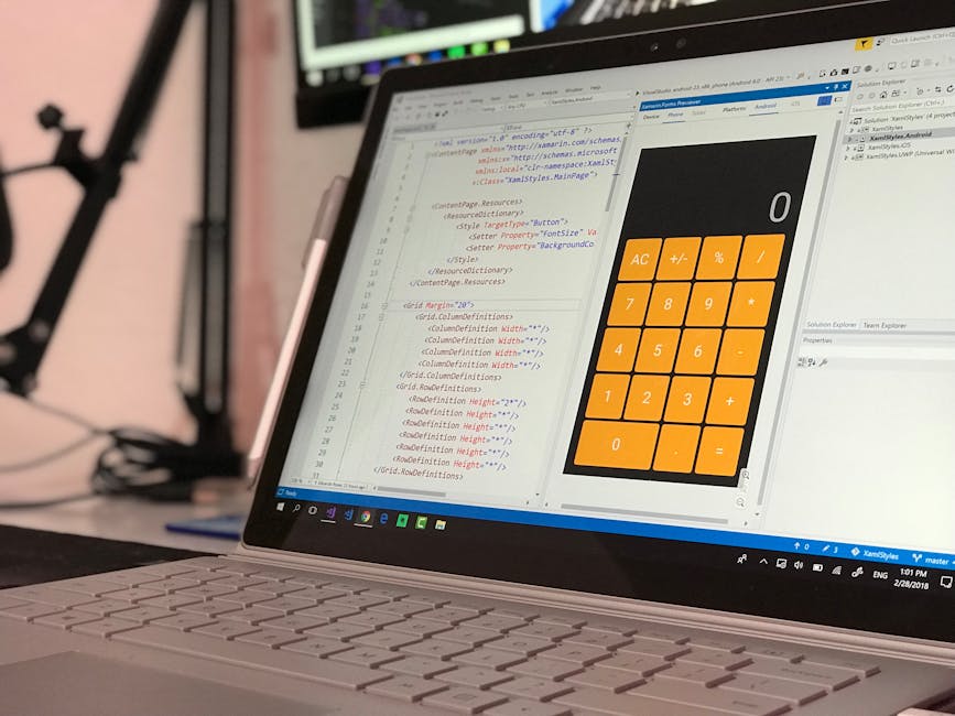 Close-up image of a laptop computer displaying a software development environment with lines of code in HTML and CSS on the left side of the screen, and a large orange calculator interface with button